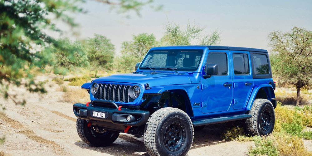 Rugged blue Jeep Wrangler 2024 for rent in Dubai offering off-road capability modern features and an adventurous open-top driving experience